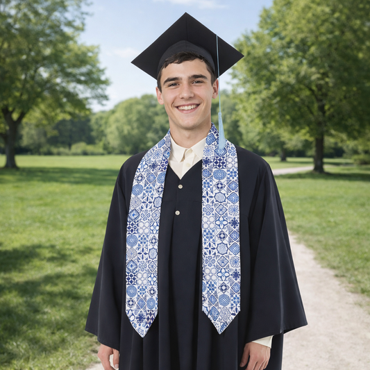 Graduate in cap and gown with a patterned stole standing outdoors on a sunny day.