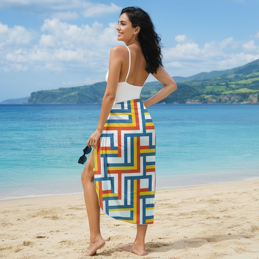 Woman on a beach wearing a colorful geometric patterned sarong with a white top.