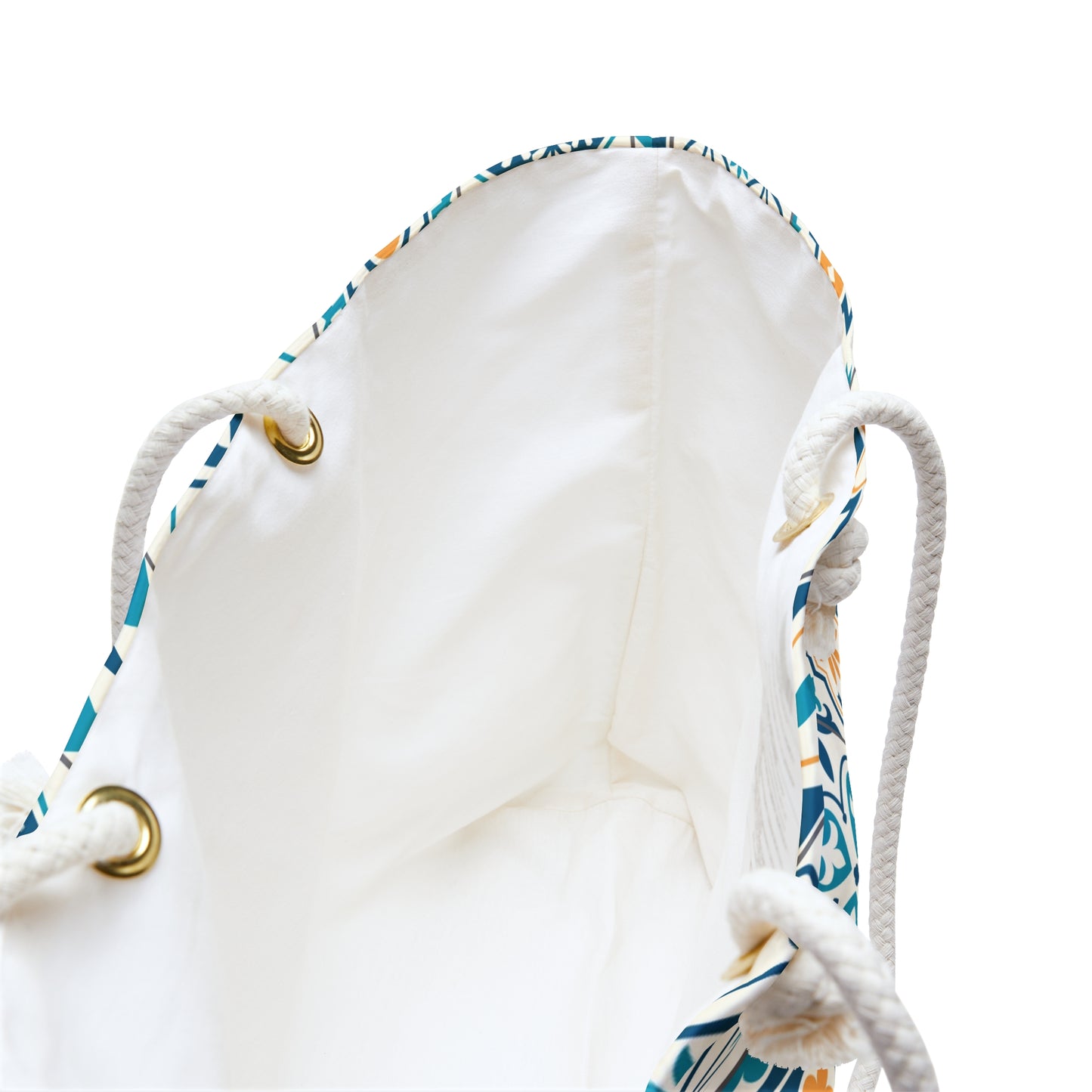 Close-up of a white drawstring bag with a blue, teal, and beige patterned trim, white rope handles, and gold-tone metal grommets on a white background.