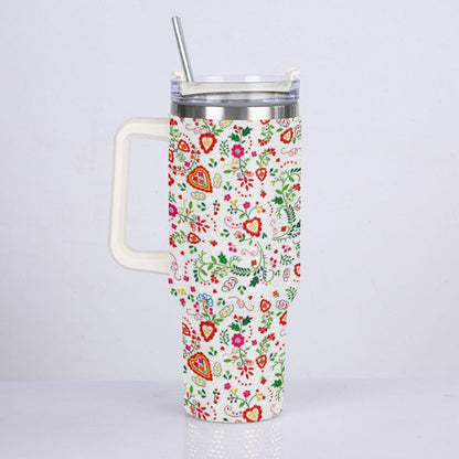A handled stainless steel travel tumbler with a clear lid and metal straw, covered in a colorful floral and heart pattern on a white background.