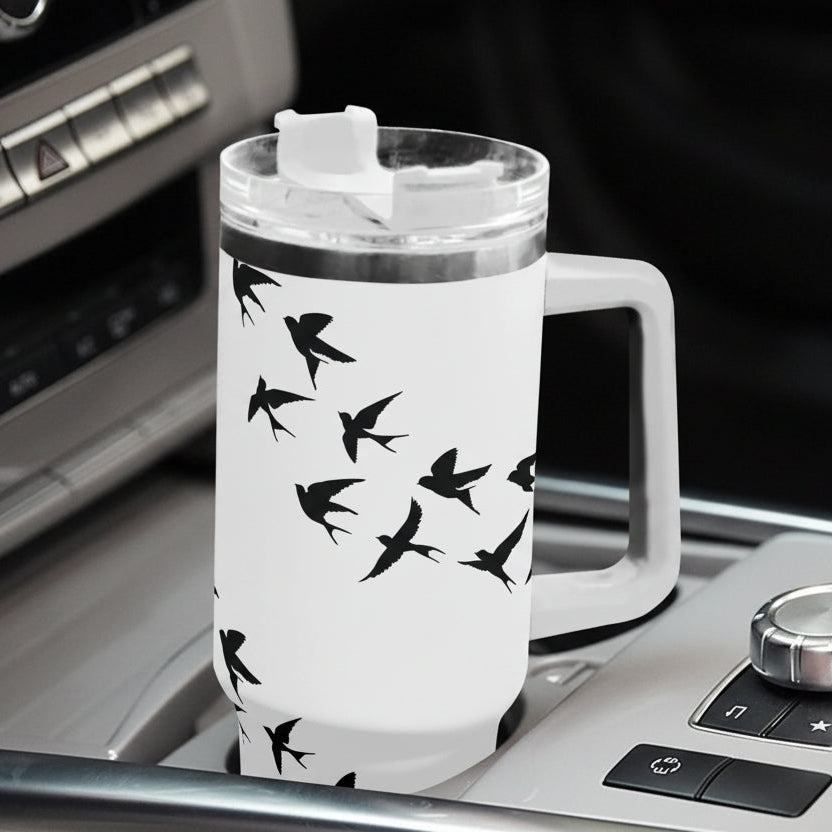 White travel mug with black bird design on a car dashboard