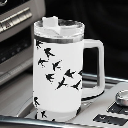 White travel mug with black bird design on a car dashboard
