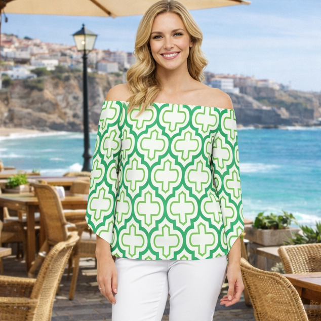 Woman in a green and white patterned top standing in an outdoor cafe with ocean view