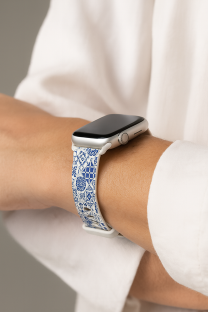Smartwatch with a blue and white tile patterned band on a person's wrist, wearing a white shirt.