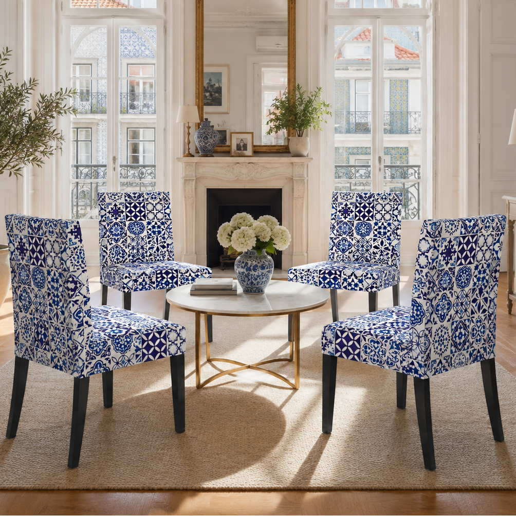 A styled dining area in a bright, classic room featuring four blue and white patterned dining chairs arranged around a round white coffee table with a gold base, set on a beige rug.