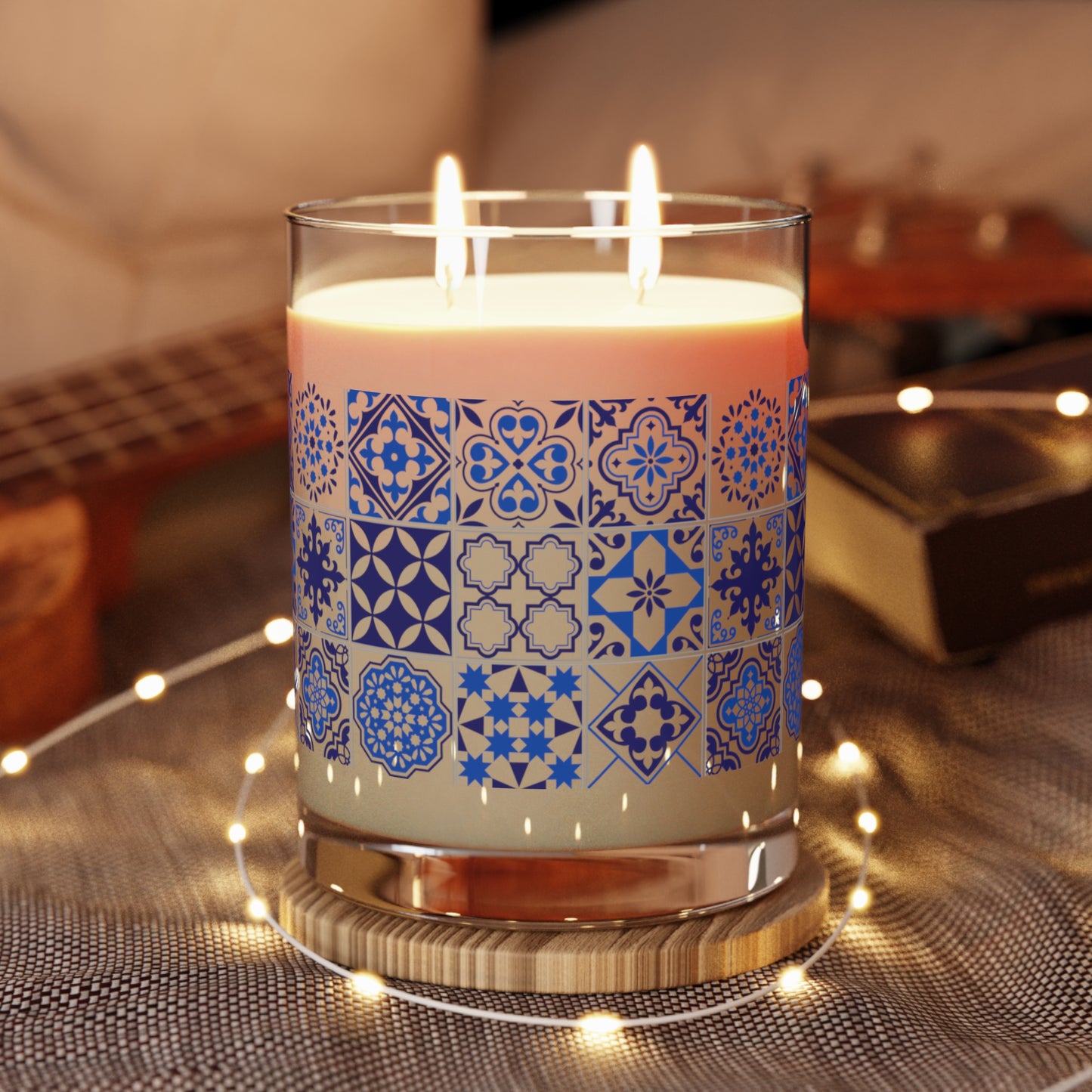 Candle with blue portuguese tile pattern in a glass holder on a textured surface with blurred background