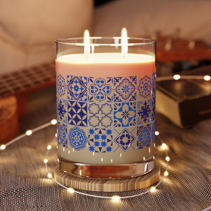 Candle with blue portuguese tile pattern in a glass holder on a textured surface with blurred background