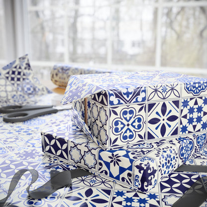 Stack of wrapped presents with blue and white azulejo pattern on a table.