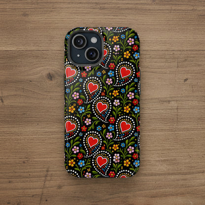 A phone case featuring a traditional Swedish folk art pattern with red hearts, white dots, and colorful flowers on a black background, shown on a plain white studio background.