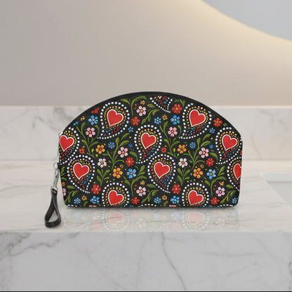 A black zippered pouch with a colorful folk-art style pattern featuring red hearts, green leaves, and small flowers, shown on a plain white background.
