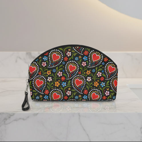 A black zippered pouch with a colorful folk-art style pattern featuring red hearts, green leaves, and small flowers, shown on a plain white background.