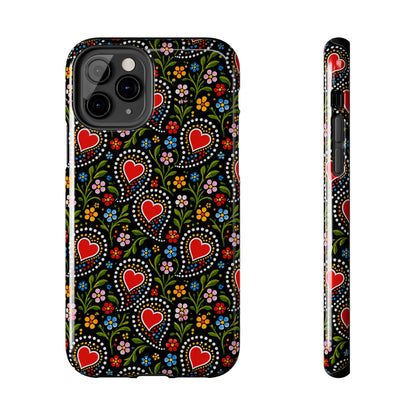 A phone case with a colorful folk-art style pattern featuring red hearts, flowers, and dots on a black background, shown from the back and side on a white background.
