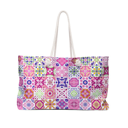 A tote bag featuring a colorful mosaic tile pattern in pink, purple, blue, green, and orange, with white rope handles and white decorative buttons on the front, set against a plain white background.