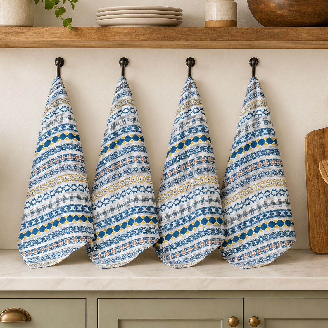 Four patterned blue and white towels hanging on a wooden shelf with kitchen items below.
