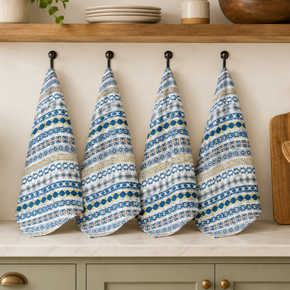 Four patterned blue and white towels hanging on a wooden shelf with kitchen items below.