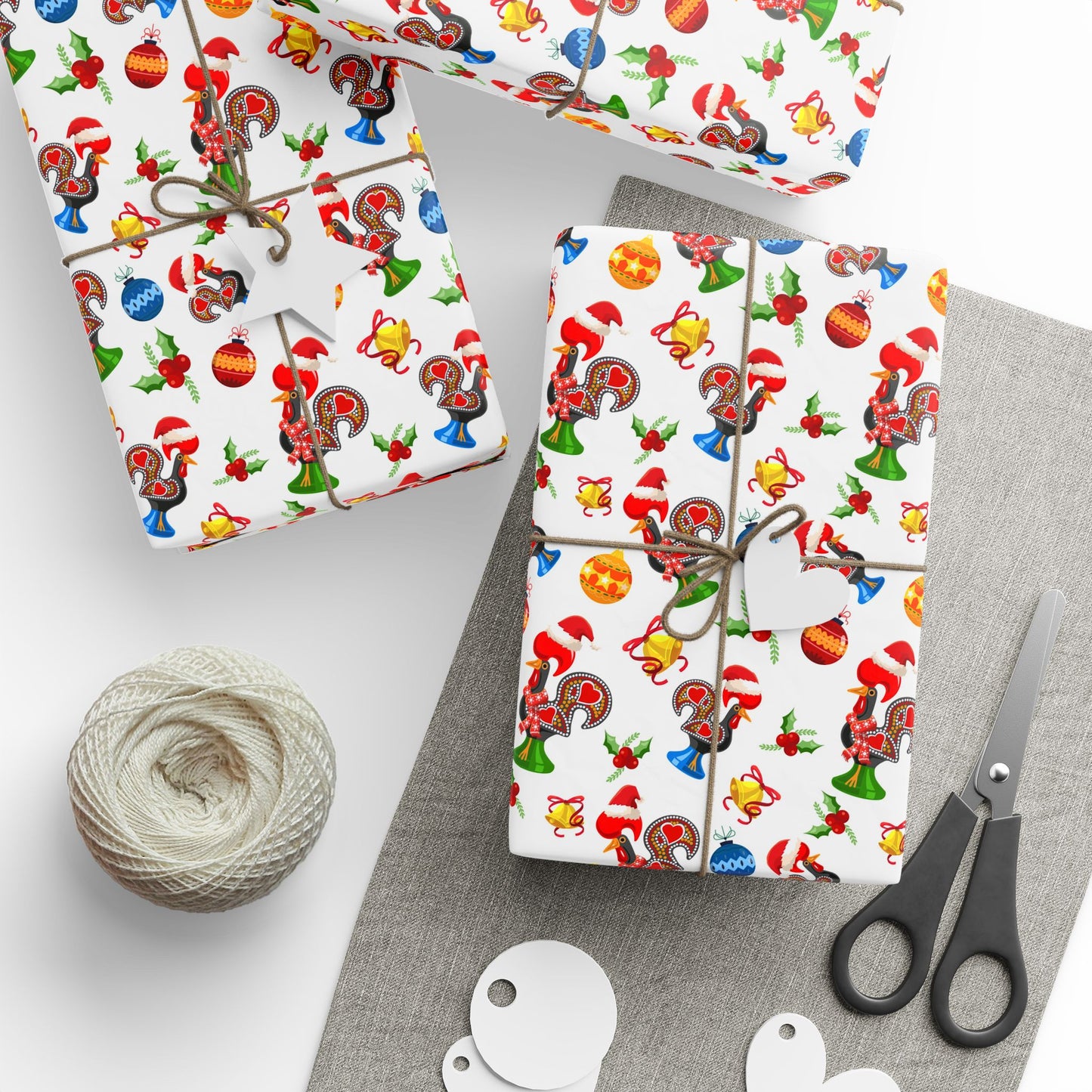 Two wrapped presents with festive galo de barcelos christmas design, string, scissors, and twine on a gray surface.