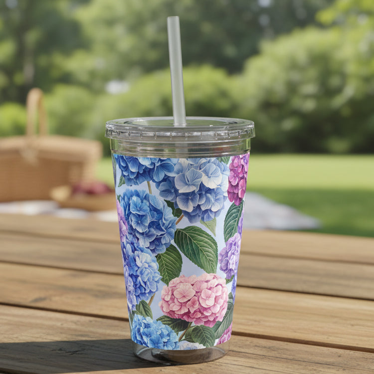 Floral-patterned tumbler with a straw on a desk next to a laptop.