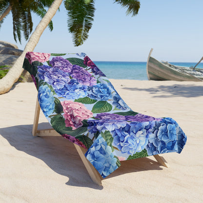 Floral-patterned towel draped over a beach chair on a sandy beach with palm trees and ocean in the background.