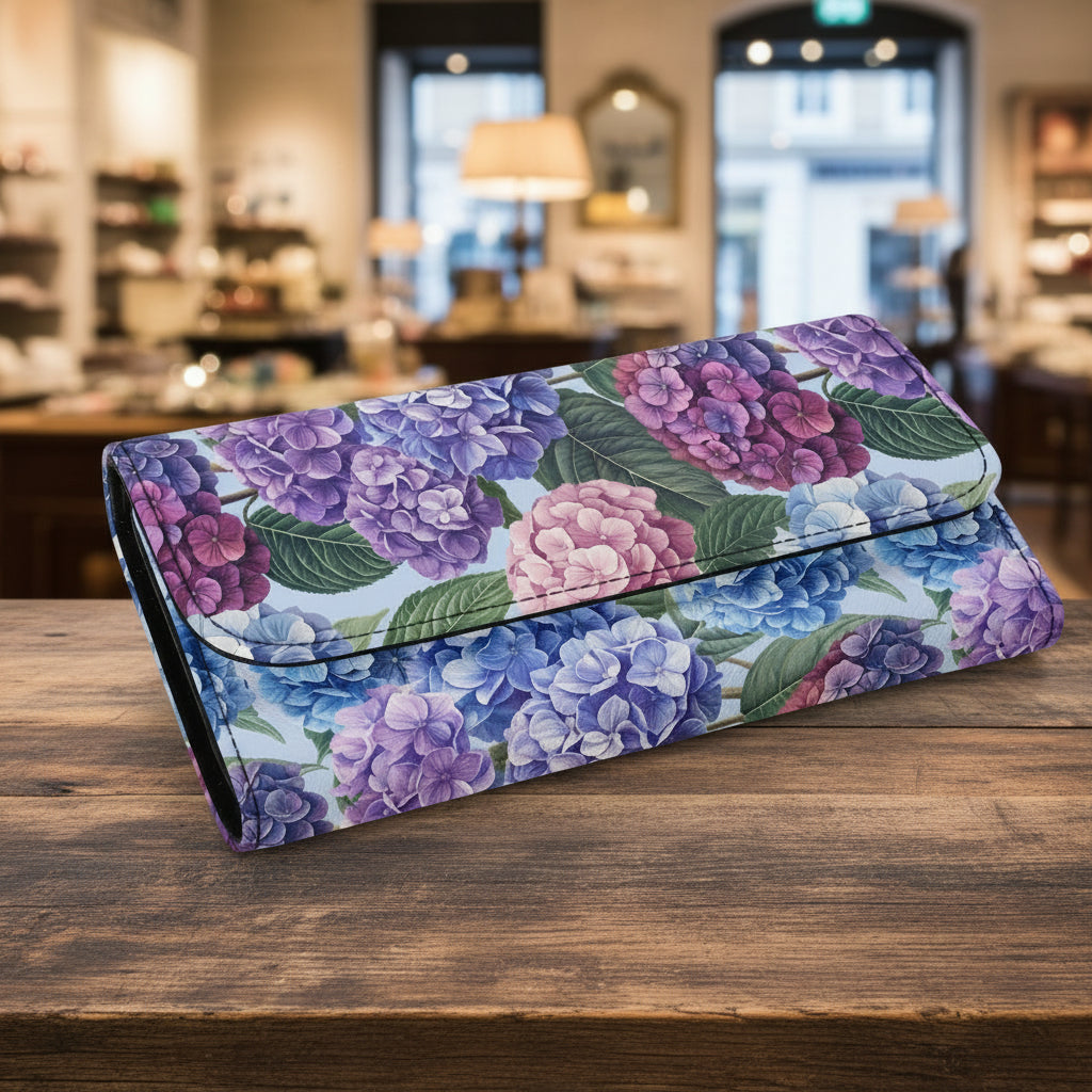 A long wallet or clutch with a floral print featuring purple, blue, and pink hydrangeas with green leaves on a white background.