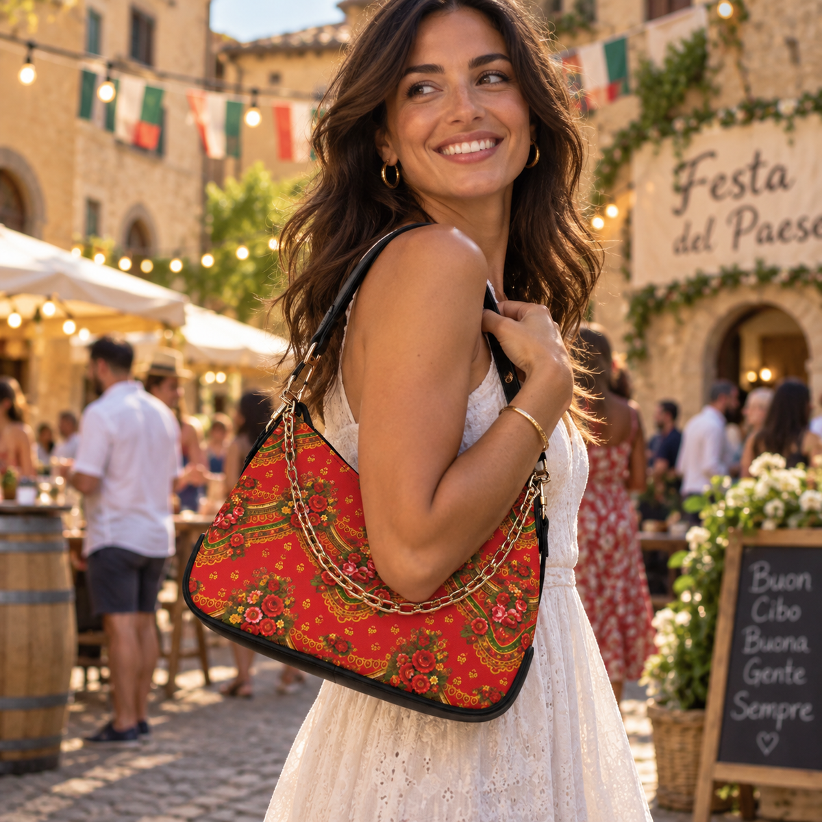 A woman in a white dress carrying a red patterned shoulder bag with gold chain detailing, set in an outdoor Italian market scene.