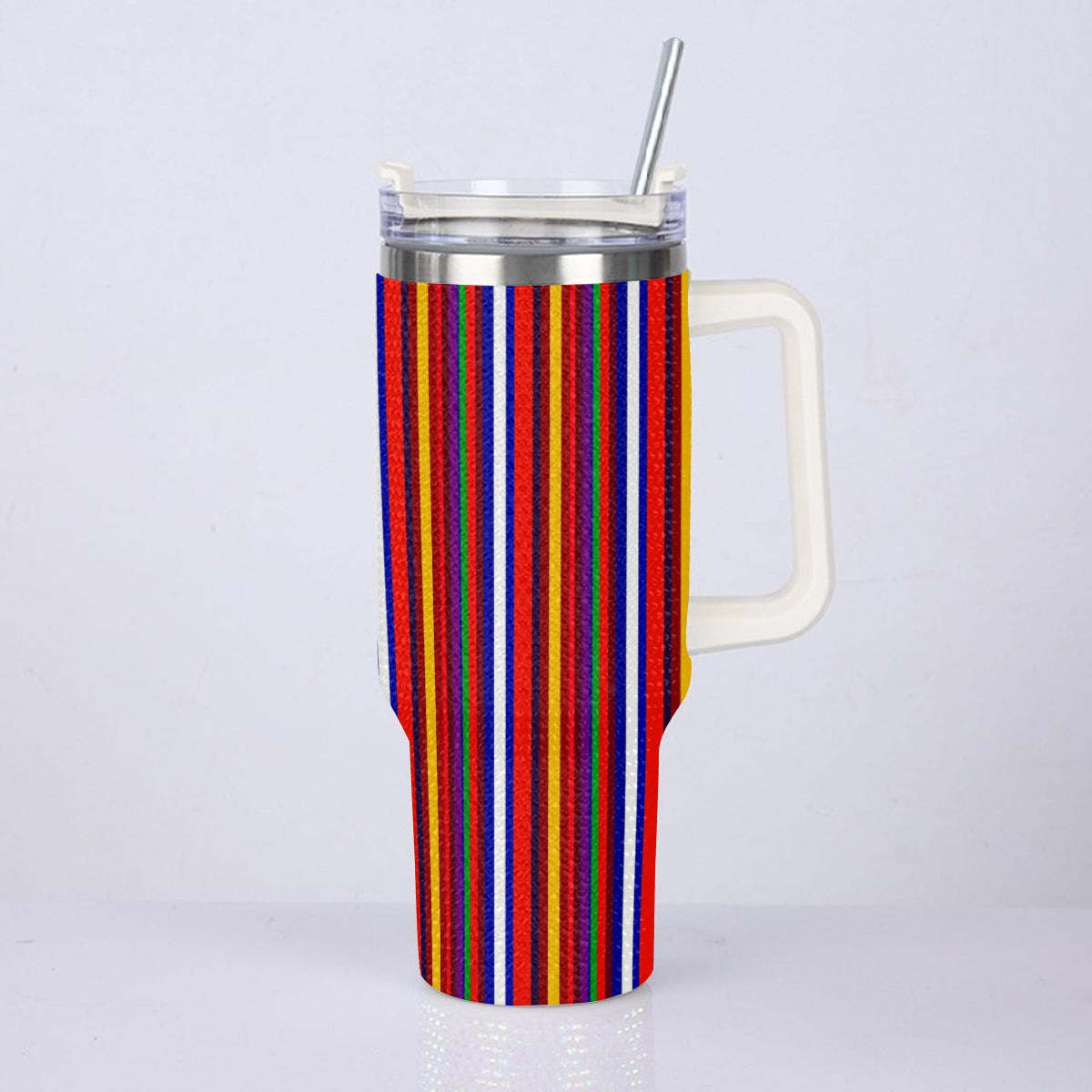 A tall handled tumbler with a colorful vertical stripe pattern in red, blue, yellow, orange, and white, featuring a clear lid with a metal straw, set against a plain light gray background.
