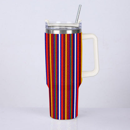 A tall handled tumbler with a colorful vertical stripe pattern in red, blue, yellow, orange, and white, featuring a clear lid with a metal straw, set against a plain light gray background.
