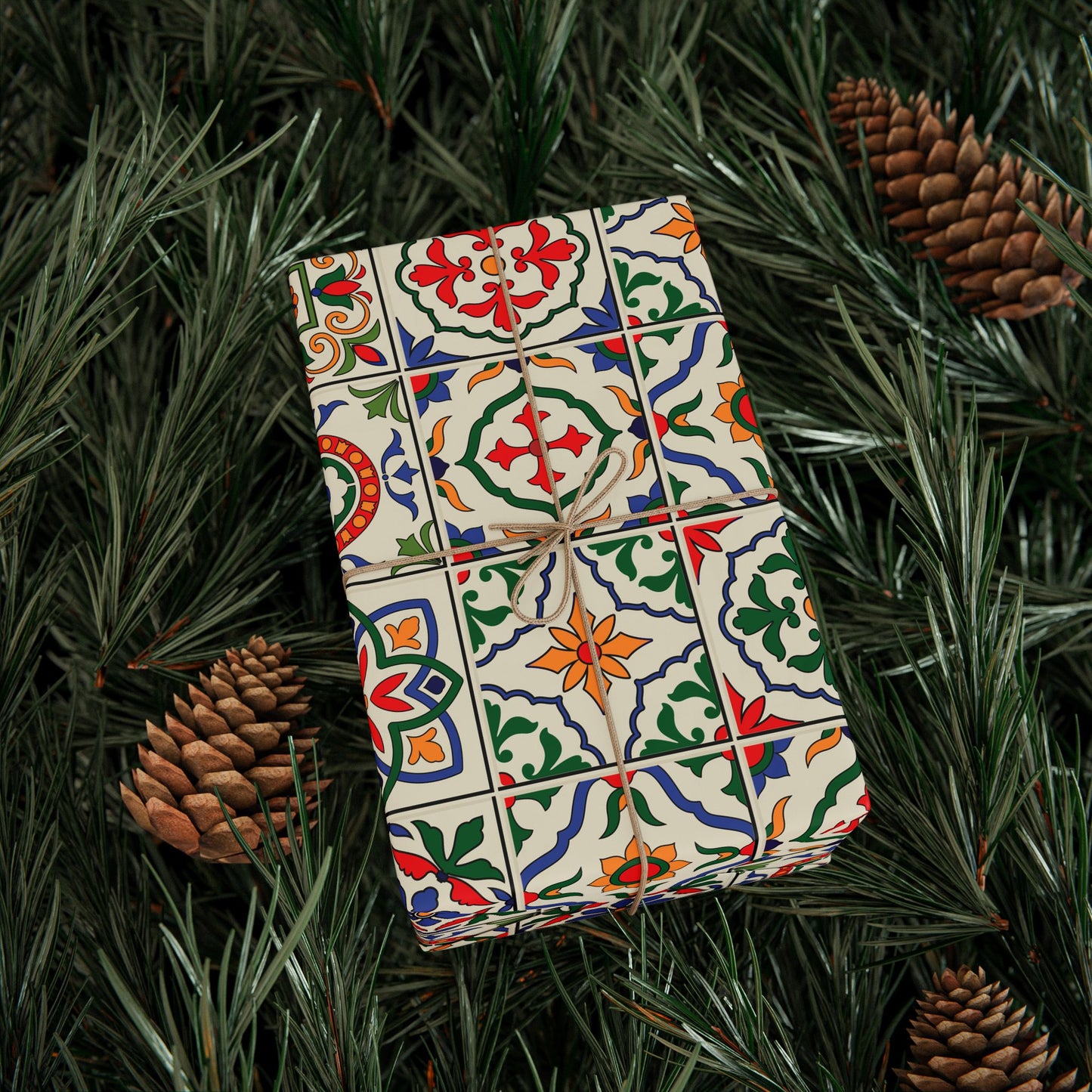 Decorative gift box with colorful portuguese tile pattern on a bed of pine needles and pine cones.