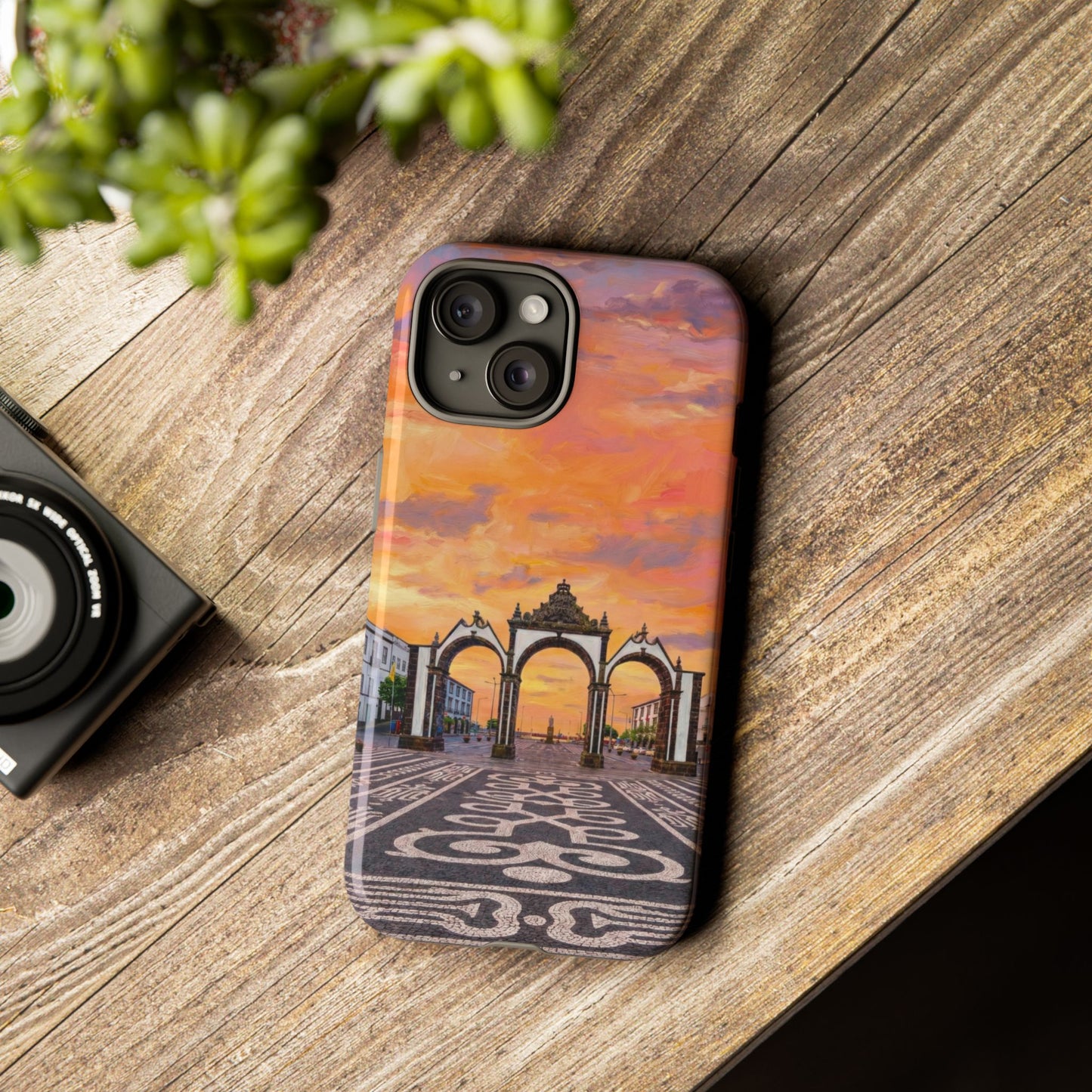 Phone case with architectural design on a wooden surface next to a camera