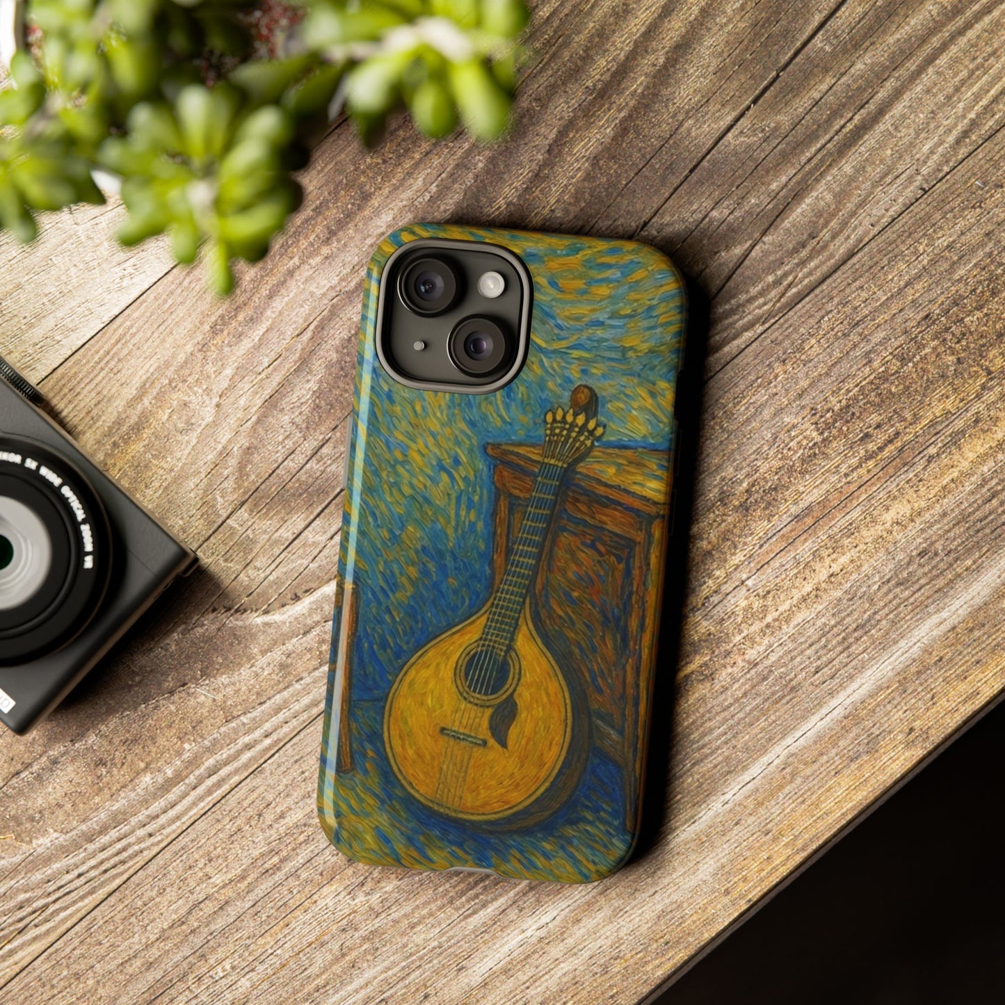 Phone case with mandolin design on a wooden surface next to a camera