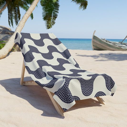 Beach towel with a wave pattern draped over a wooden chair on a sandy beach.