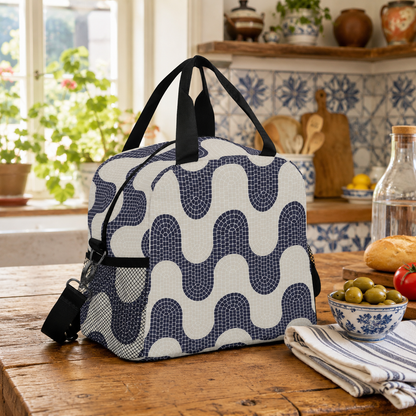 A reusable lunch bag with a navy and off-white wavy geometric pattern sits on a rustic wooden table in a bright kitchen setting.