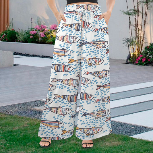 Women's resort wear wide-leg pants featuring a whimsical Portuguese Sardine fish print, perfect for beach vacations and summer travel. These comfortable palazzo pants are made from lightweight fabric and paired with a crop top for a chic, sunny holiday outfit.