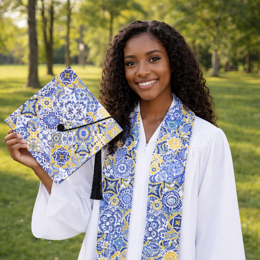 Graduate holding a decorated cap and wearing a matching scarf outdoors.