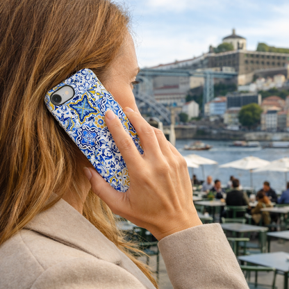 Person holding a phone with a colorful case, overlooking a scenic city view with water and buildings.