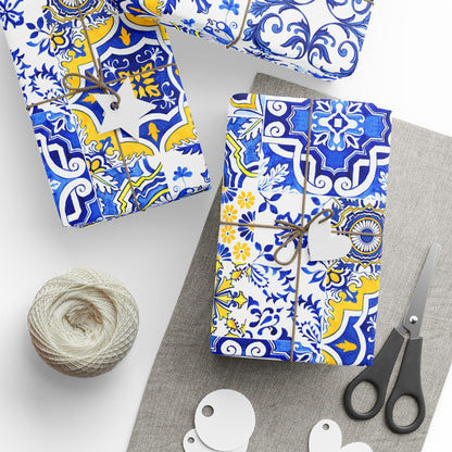 Gift boxes wrapped in blue and yellow portuguese azulejo patterned paper with scissors and twine on a white surface.