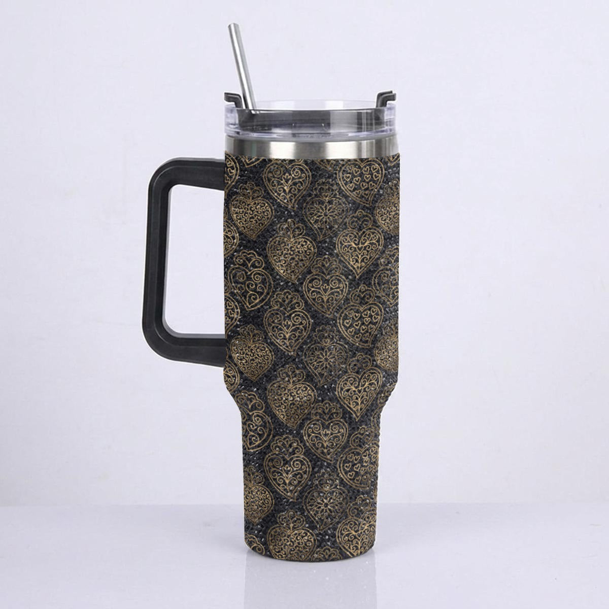 A tall insulated tumbler with a black handle and lid, featuring a decorative gold and black damask pattern sleeve, shown on a light gray background with a clear lid and metal straw.