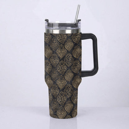 A handled travel tumbler with a black handle and a clear lid with a metal straw, featuring a dark brown and gold damask pattern wrap, shown against a plain white background.