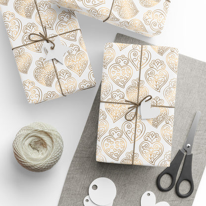 Gift boxes wrapped in gold heart of viana portugal patterned paper with string, scissors, and yarn on a white background