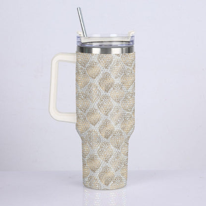 A tall handled travel tumbler with a snakeskin pattern in beige and white, featuring a clear lid with a silver metal straw, set against a plain light gray background.