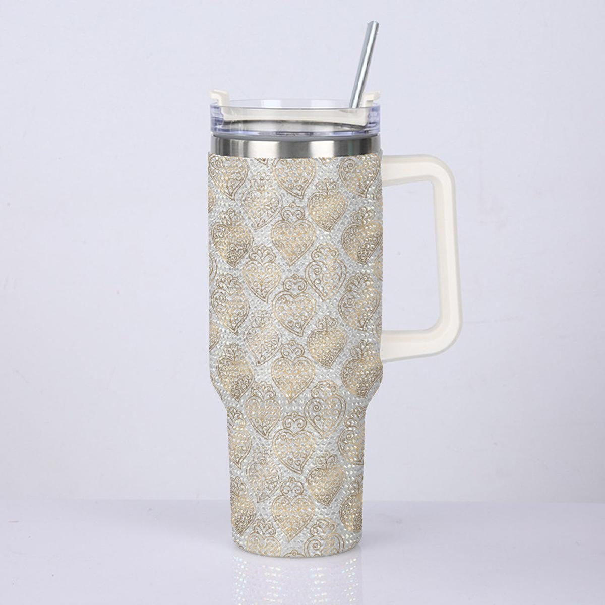 A handled travel tumbler with a beige and white damask pattern, featuring a clear lid with a silver metal straw, set against a plain light gray background.