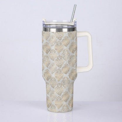A handled travel tumbler with a beige and white damask pattern, featuring a clear lid with a silver metal straw, set against a plain light gray background.