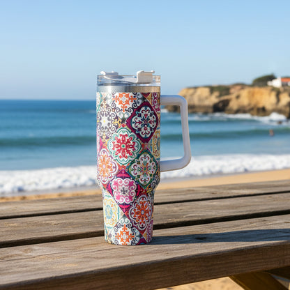 A 40oz stainless steel tumbler with a colorful Portuguese tile-inspired pattern, featuring a handle and a lid, placed in a car's cup holder.