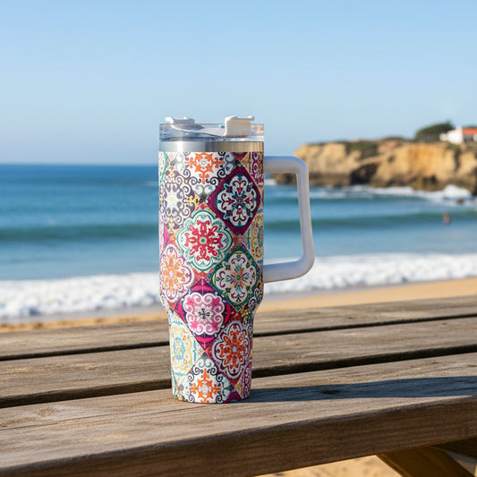 A 40oz stainless steel tumbler with a colorful Portuguese tile-inspired pattern, featuring a handle and a lid, placed in a car's cup holder.