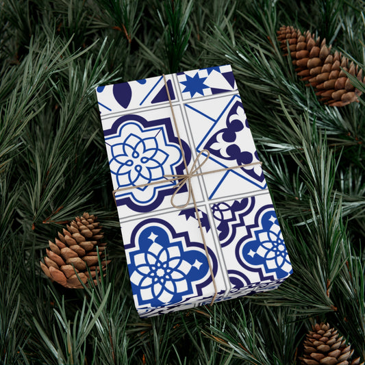 Gift wrapped in blue and white patterned paper with string, surrounded by pine branches and pinecones.