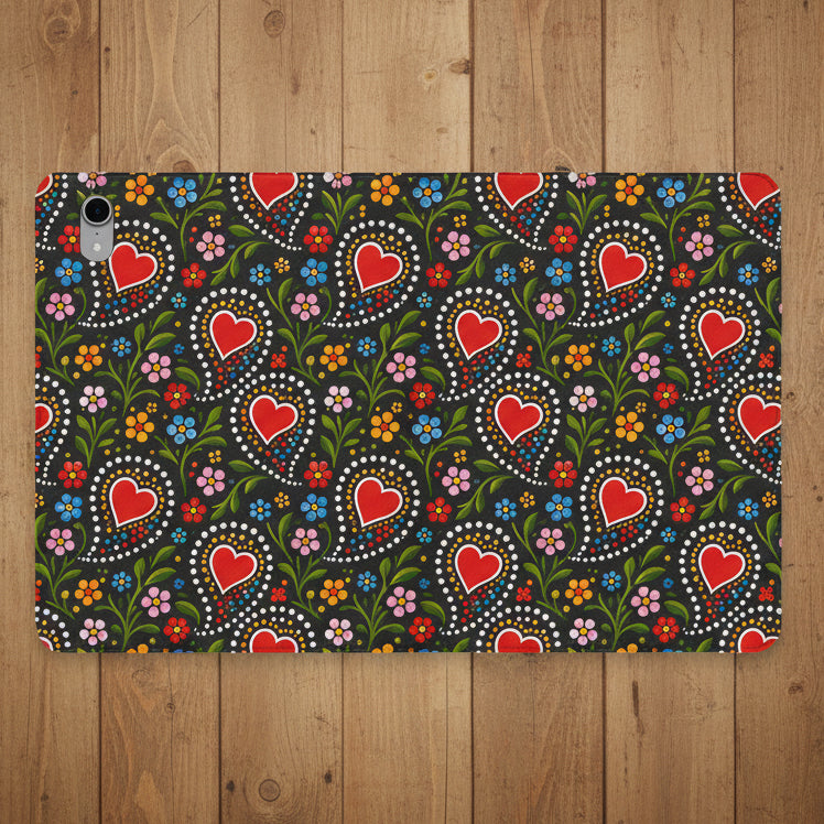 A protective tablet case featuring a dense folk-art style pattern of red hearts, green leaves, and colorful flowers on a dark background.