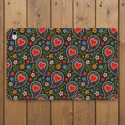 A protective tablet case featuring a folk-art style pattern of red hearts, green leaves, and colorful flowers on a dark background, shown against a plain white studio backdrop.