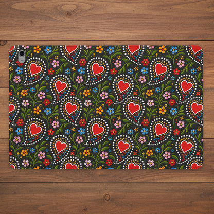 A protective case for an iPad, featuring a colorful folk-art style pattern with red hearts, green leaves, and small flowers on a dark background.