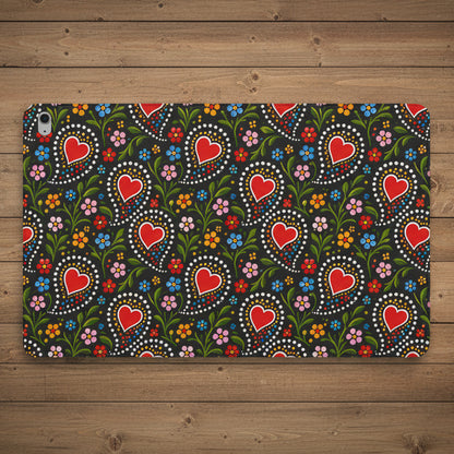 A protective case for an iPad, featuring a vibrant folk-art style pattern with red hearts, green leaves, and multicolored flowers on a dark background.