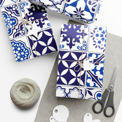 Gift boxes wrapped in blue and white patterned paper with scissors and yarn on a white surface.