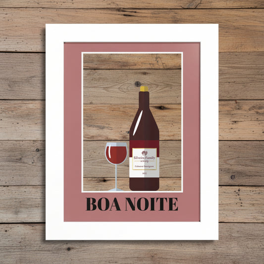 A framed art print featuring a minimalist illustration of a wine bottle and a glass of red wine against a blue background, surrounded by a dusty rose inner border and a white frame. The text 'BOA NOITE' is printed at the bottom.